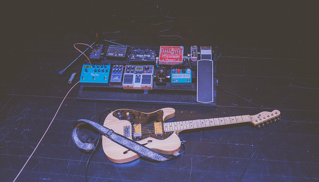 Guitarra eléctrica conectada a un pedal de efectos sobre un escenario