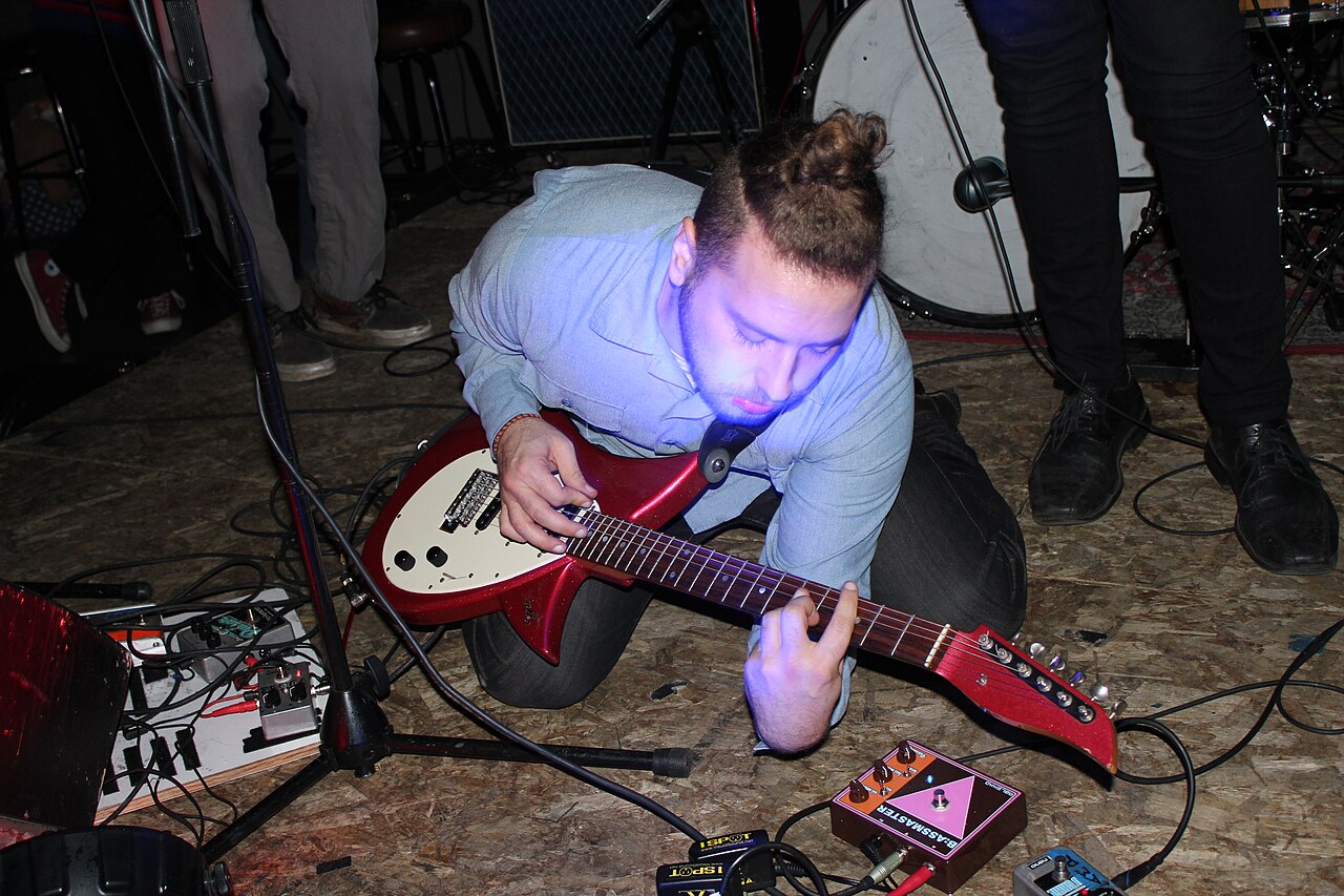 Cantautor tocando la guitarra sobre un escenario durante una presentación en vivo