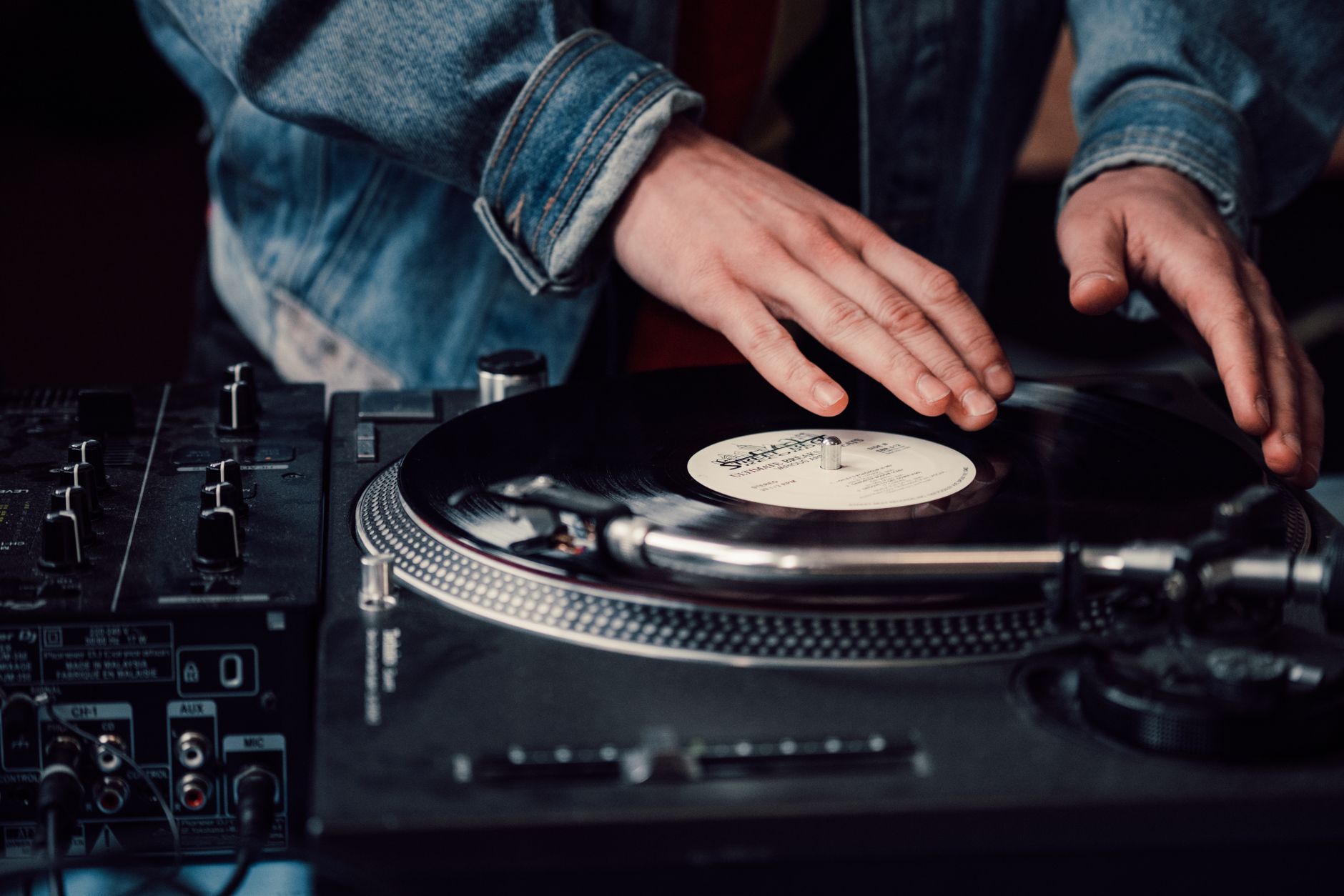 DJ mezclando discos de vinilo en una tornamesa, imagen ilustrativa del álbum oficial de GTA VI con artistas de varios géneros
