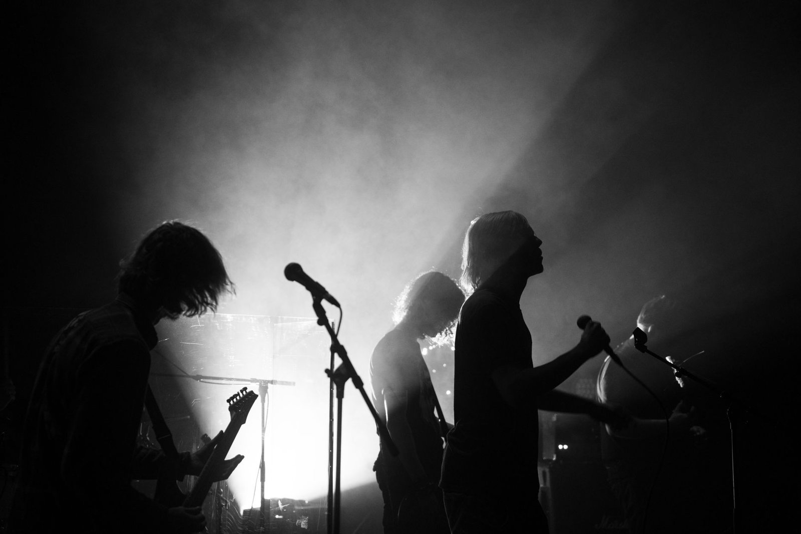 Silueta de una banda tocando en vivo con luces dramáticas, imagen ilustrativa para Lana Del Rey Zach Bryan Lies