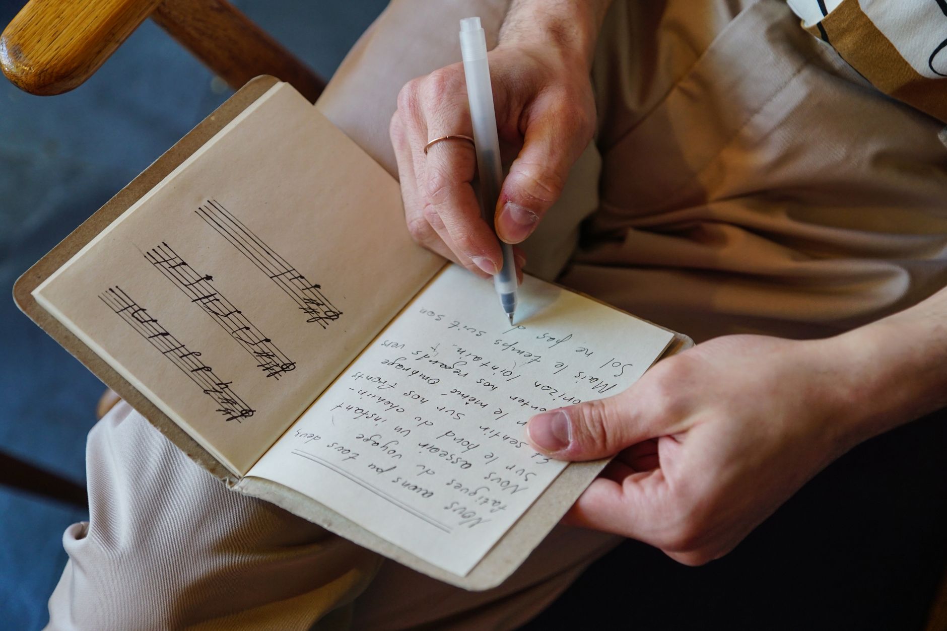 Hombre escribiendo letras y notas musicales en un cuaderno, imagen ilustrativa de las letras inéditas de Woody Guthrie