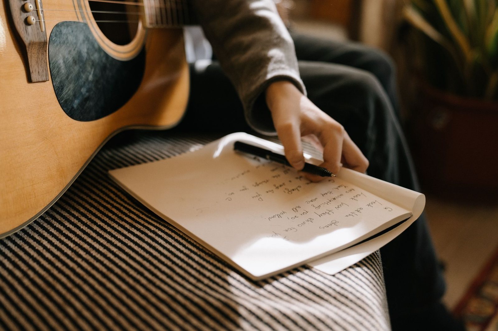 Persona escribiendo canciones en un cuaderno junto a una guitarra, ilustra el proceso creativo defendido por Olivia Rodrigo