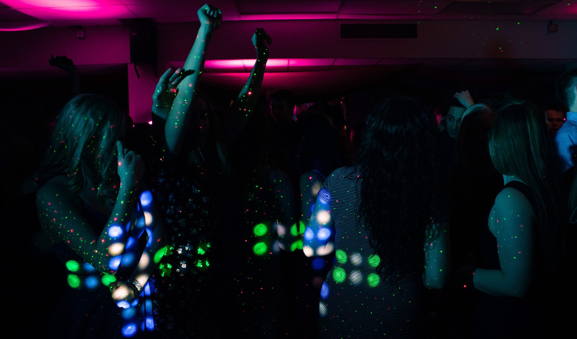 Escena de un club nocturno con personas bailando bajo luces de colores, imagen ilustrativa del sonido dance de Troye Sivan